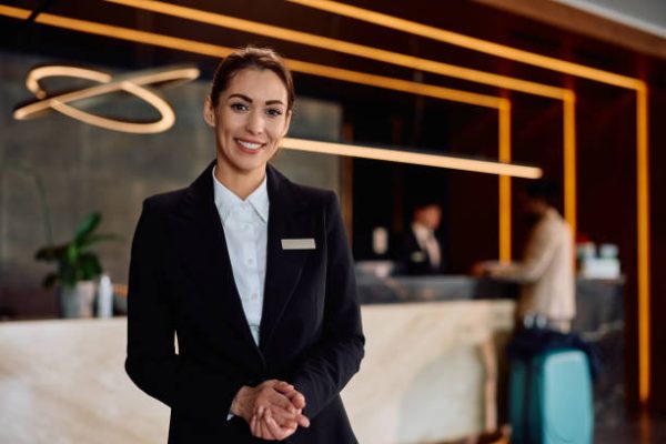 Smiling female hotel receptionist in a hallway looking at camera. Copy space.